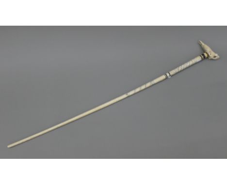 A 19th century whale bone walking stick with carved marine ivory handle formed as a walrus. 92.5 cm long.