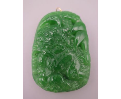 A gold mounted jade pendant.  6 cm high. 