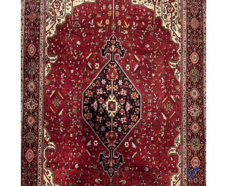 Persian carpets: A finely knotted Oriental carpet with a dark red background. | 226 x 142 cm.