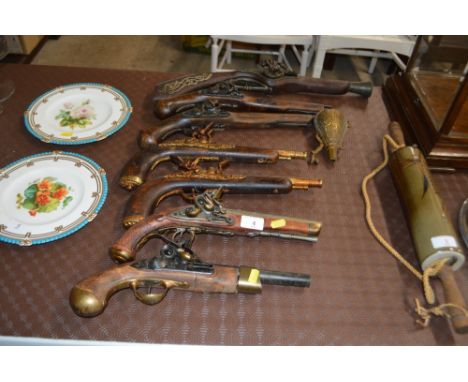 Seven replica pistols and a powder flask 