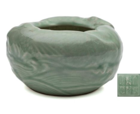 A Chinese celadon brush washer: of circular form moulded with two carp swimming amongst waves, apocryphal six-character Qianl