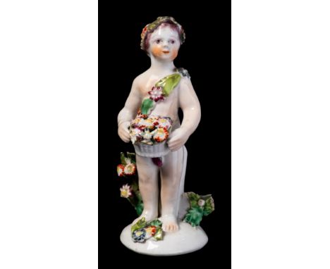A Bow figure of a putto: holding a basket of flowers and wearing a floral headdress and sash, circa 1765, 13 cm [losses to bo