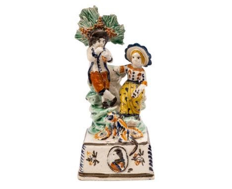 An unusual Prattware pottery commemorative group: of rural child musicians with bocage support, the boy playing a flute, the 