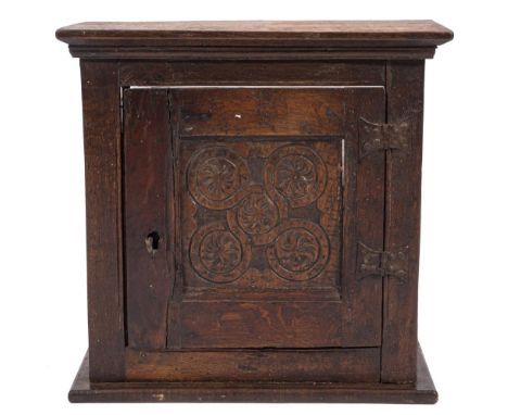 A late 17th Century oak spice cupboard:, with a moulded cornice and interior shelf, enclosed by an incised carved guilloche a