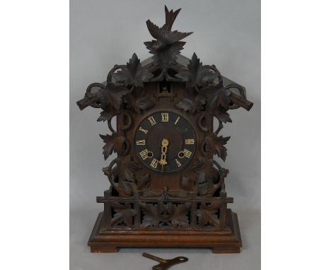 A Junghans Black Forest style cuckoo mantel clock, carved case and maker's mark to the back and with key and pendulum. H.55.5