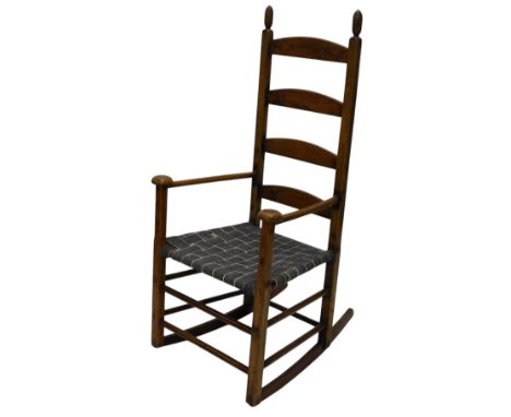 A 19thC beech and pine ladder back rocking chair, with a woven seat, shaped arms and turned stretchers, previously painted, e