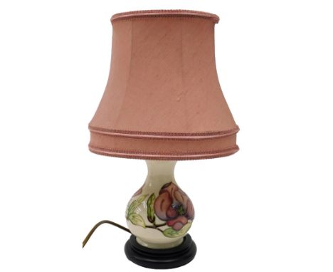 A Moorcroft table lamp, decorated with the pink flower design, on a cream ground with pink shade, 38cm high.