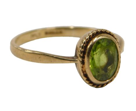 A 9ct gold peridot set dress ring, the oval peridot in rub over setting, with rope twist border, ring size Q½, 2.2g all in.