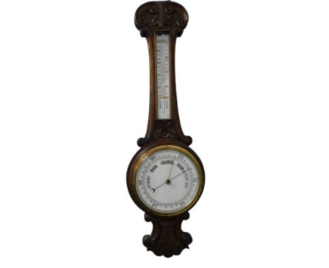 A late 19th/early 20thC carved oak wheel barometer, with ceramic dial and thermometer, 84cm high.