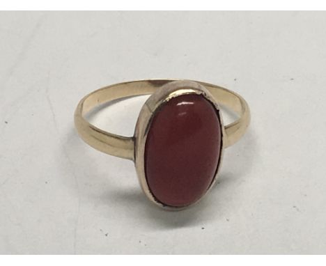 An unmarked gold ring set with an oval cabochon. Ring size R.