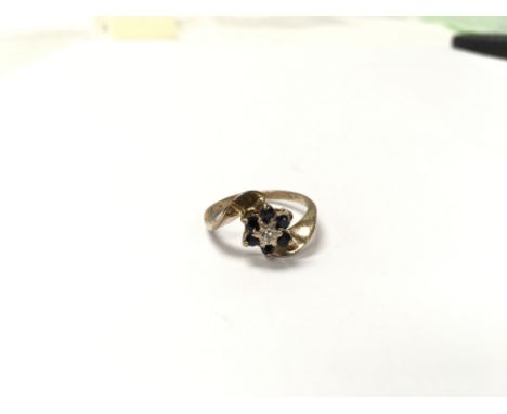 A gold ring set with sapphires and a small diamond in the shape of a flower. The approximate ring size is N  - NO RESERVE