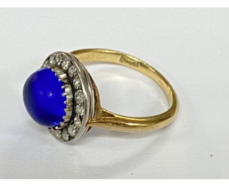 An 18ct gold ring set with a blue cabochon stone surrounded by brilliant cut diamonds.