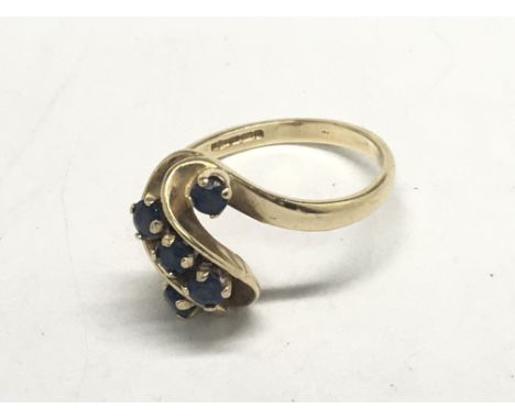 A 9ct gold ring set with a scrolling row of sapphire. ring size R Weight 4g