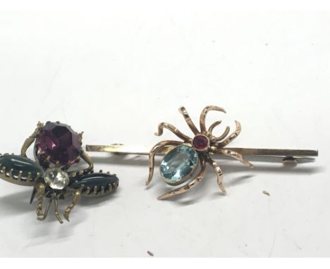 A gold bar brooch in the form of a spider set with an aquamarine coloured stone and ruby and one other gold tone insect brooc