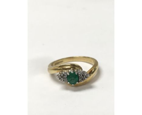 An 18ct gold emerald ring, set with small diamonds. The approximate ring size is P.