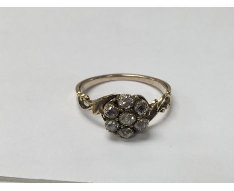 An unmarked gold ring set with diamonds in the shape of a flower. The approximate ring size is O.