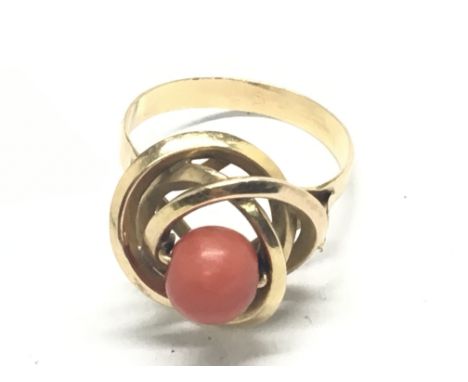 An unmarked gold ring set with a coral bead. Ring size R. Weight 3.8g