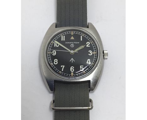 A 1973 issued Hamilton W10 British Army issued military wristwatch. Black dial with luminescent Arabic numerals, broad arrow 