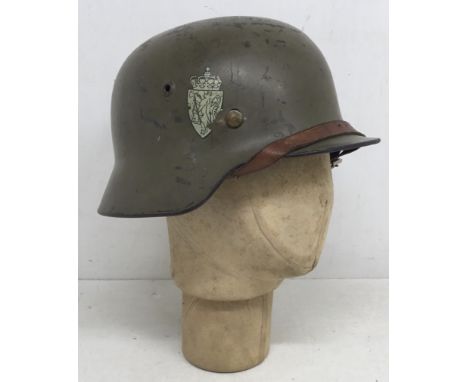 A WW2 made, German M40 helmet, reused by Norwegian forces in the post war era. Of usual form, with the rim rolled under, and 