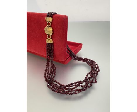 A late 19th century five-strand ruby bead necklace, the uniform strands on an unmarked engraved yellow metal clasp, further e
