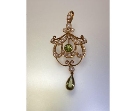 An Edwardian 15ct gold peridot and seed pearl pendant, the pear-cut and round-cut peridots each millegrain set and suspended 