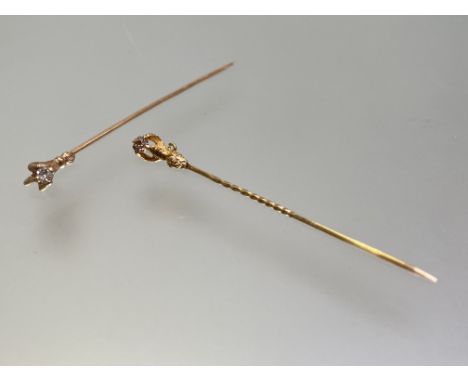 Two single stone diamond stick pins, c. 1900, each mounted in yellow metal (unmarked) as a claw clutching a round brilliant c