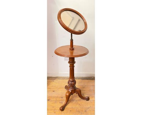 A mid-Victorian walnut shaving stand, the circular mirror plate within a conforming moulded frame, swivelling above a circula