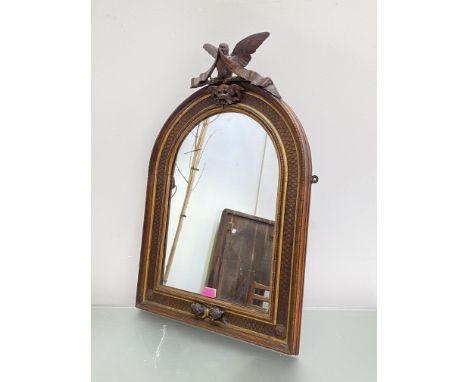 A carved walnut and parcel-gilt arched frame, now incorporating a mirror plate, 19th century, the surmount carved as a dove b