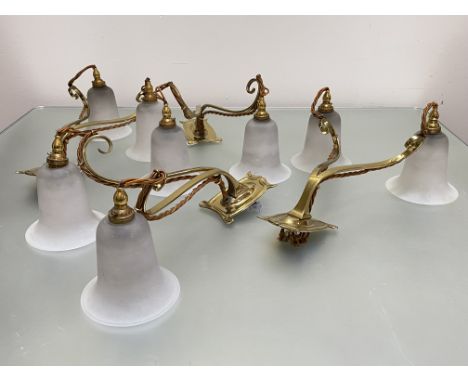 A set of four twin-light brass and opaque glass wall lights in Art Nouveau style, each shaped rectangular backplate issuing a