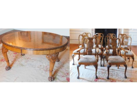 A George II style walnut extending dining table, the oval burr top with a carved edge, raised on four shell and scroll carved