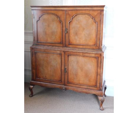 A Queen Anne style walnut cocktail cabinet, the top with a moulded edge above two hinged doors enclosing a shaped shelf picke