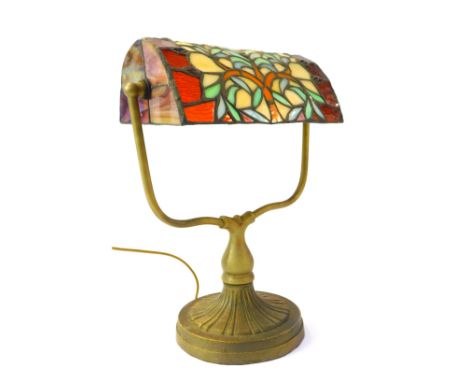 A Tiffany style desk lamp, the leaded glass shade decorated with a tree raised on a cast metal base on circular foot, 35cm hi