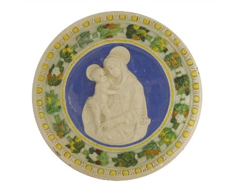 A Della Robbia pottery Madonna and Child tondo, centred with a blue ground with a moulded egg and dart and floral floral fram