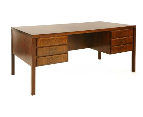 A rosewood desk, § designed by Gunni Omann, with three drawers, the top drawers with trays, the reverse with a central cupboa