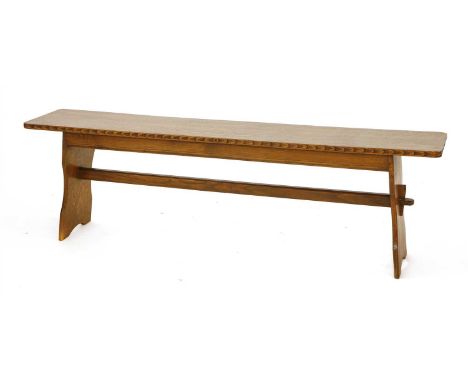 An oak bench, in the manner of Arthur Simpson, with a plain top and carved edge on strut supports, 151.5cm wide 29.5cm deep 4