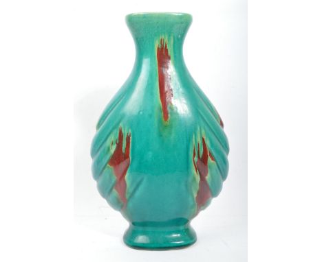 A vintage 20th century ceramic studio pottery vase having a scalloped shaped body with flared rim. Decorated with red glazed 