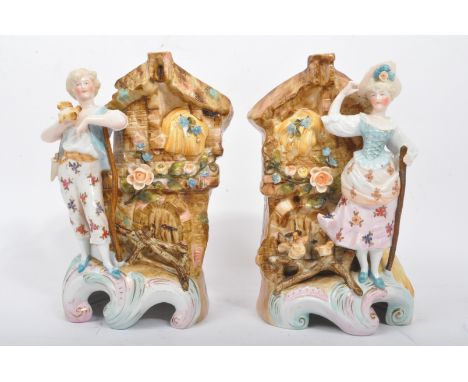 A pair of early 20th century continental hand painted bisque vases featuring shepherd and shepherdess figure modelled in reli