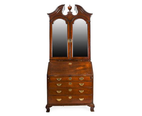 An Arched George II Mahogany Bureau Bookcase, circa 1750, the broken moulded pediment and turned finial above a sun burst mar