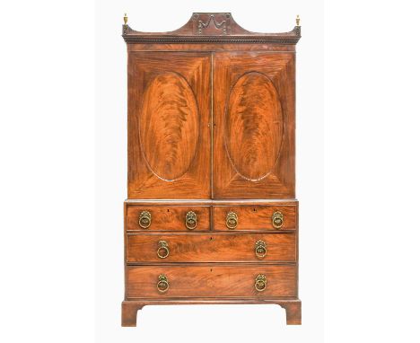 A George IV Mahogany Linen Press, 2nd quarter 19th century, the arched pediment centred by a tablet of swags above a dentil c