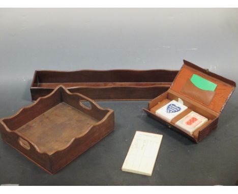 Two mahogany desk trays and a cased pack of playing cards  
