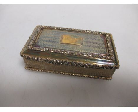 An early 19th century silver gilt presentation snuff box, the case with engine turning and floral cast border, the interior e