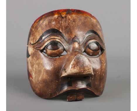 A hand-carved Indonesian-style wooden dance mask, likely from Java or Bali, with exaggerated features and remnants of origina