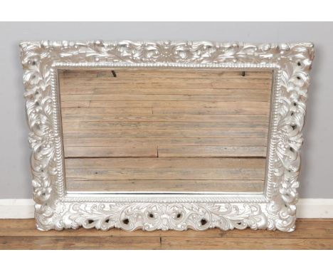 A large wall hanging bevel edged mirror, in carved decorative grey painted frame. Height: 88cm, Width: 116cm.