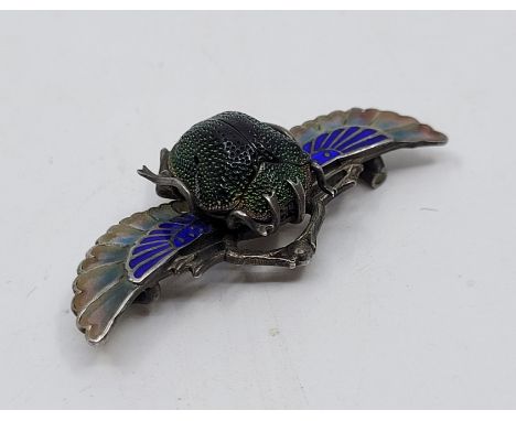 An Egyptian revival unmarked silver, cliosonne and champleve enamel scarab beetle brooch, set natural scarab to centre with b