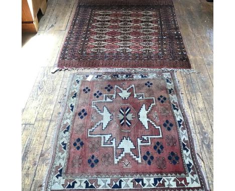 A Bokhara rug, the centre panel with three rows of seven octagons enclosed within a stylised leaf and flower border, pink fie