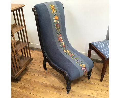 A late Victorian ebonised nursing chair with upholstered back and seat, with central fruit and flower grospoint panel, on tur