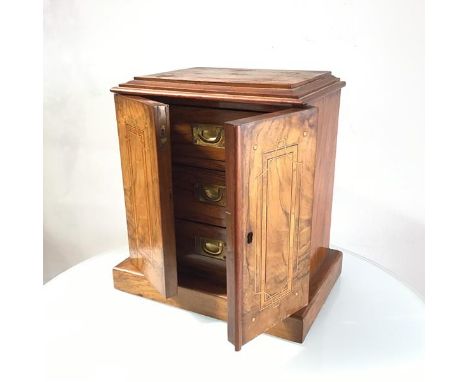 A Victorian walnut cabinet with nest of drawers, the inlaid top with moulded edge above a pair of similar inlaid panel doors,