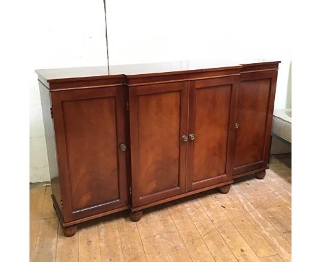 A Regency style mahogany breakfront credenza, the rectangular top above four panel doors, raised on reeded bun feet