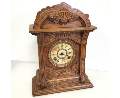 An oak mantel clock with moulded dome top above a dial with roman numerals, door to reverse with Modena label, Prize Medal Aw