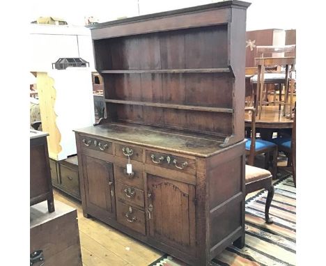 A George III elm two part dresser with plate rack back, the moulded cornice above three open shelves, above a rectangular top